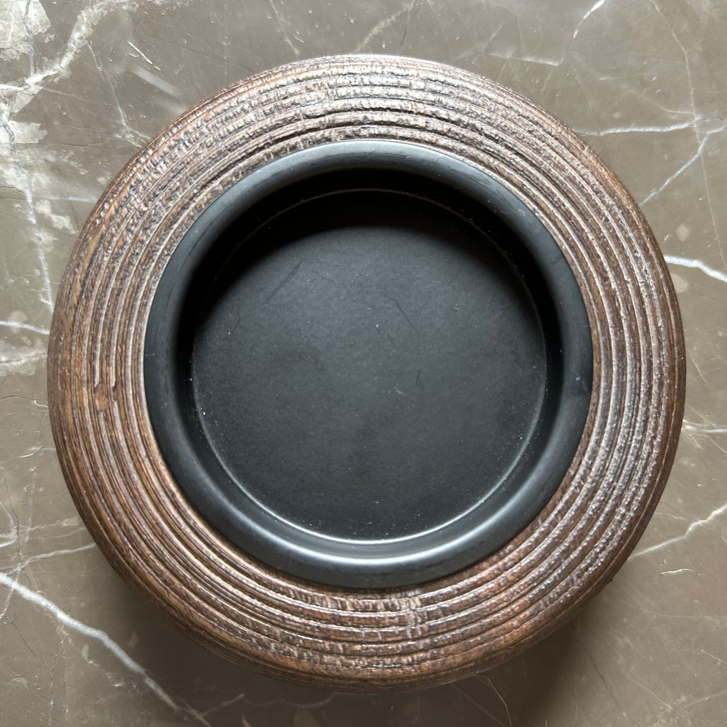 Klein, rond, gevlochten mandje op een marmeren tafel in de woonkamer, met een bank op de achtergrond.