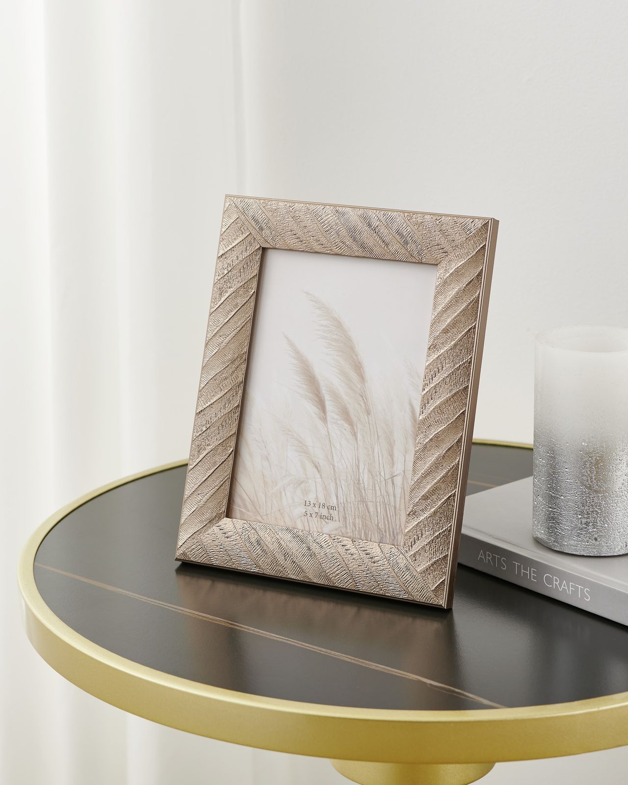 Zilverkleurige fotolijst met textuur, witte passe-partout en beige grasprint, staand op een zijstandaard.