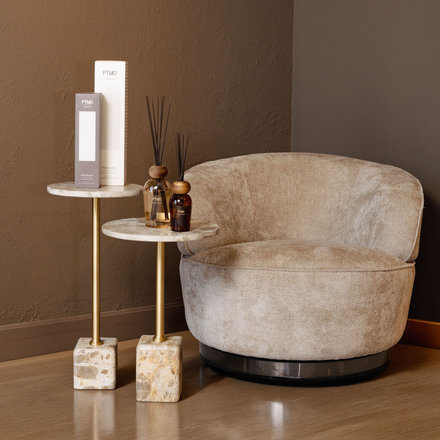 Minimalistische beige woonkamerhoek met een ronde stoel, bijzettafels en decoratieve vazen.