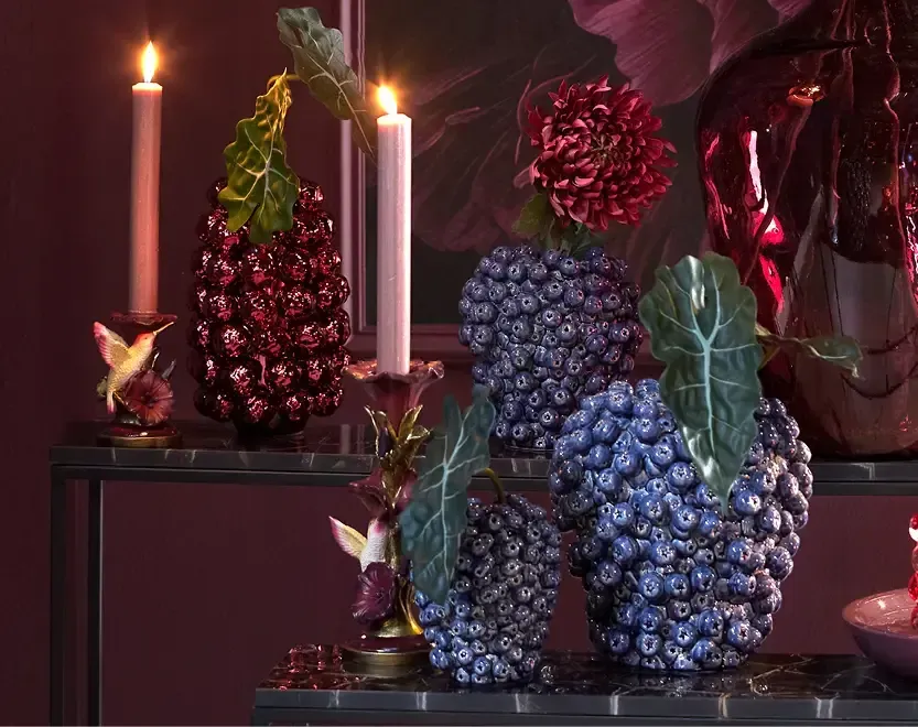 Donkere tafel met vaas met bloemen, kaarsen en fruit. Interieur in neutrale tinten.
