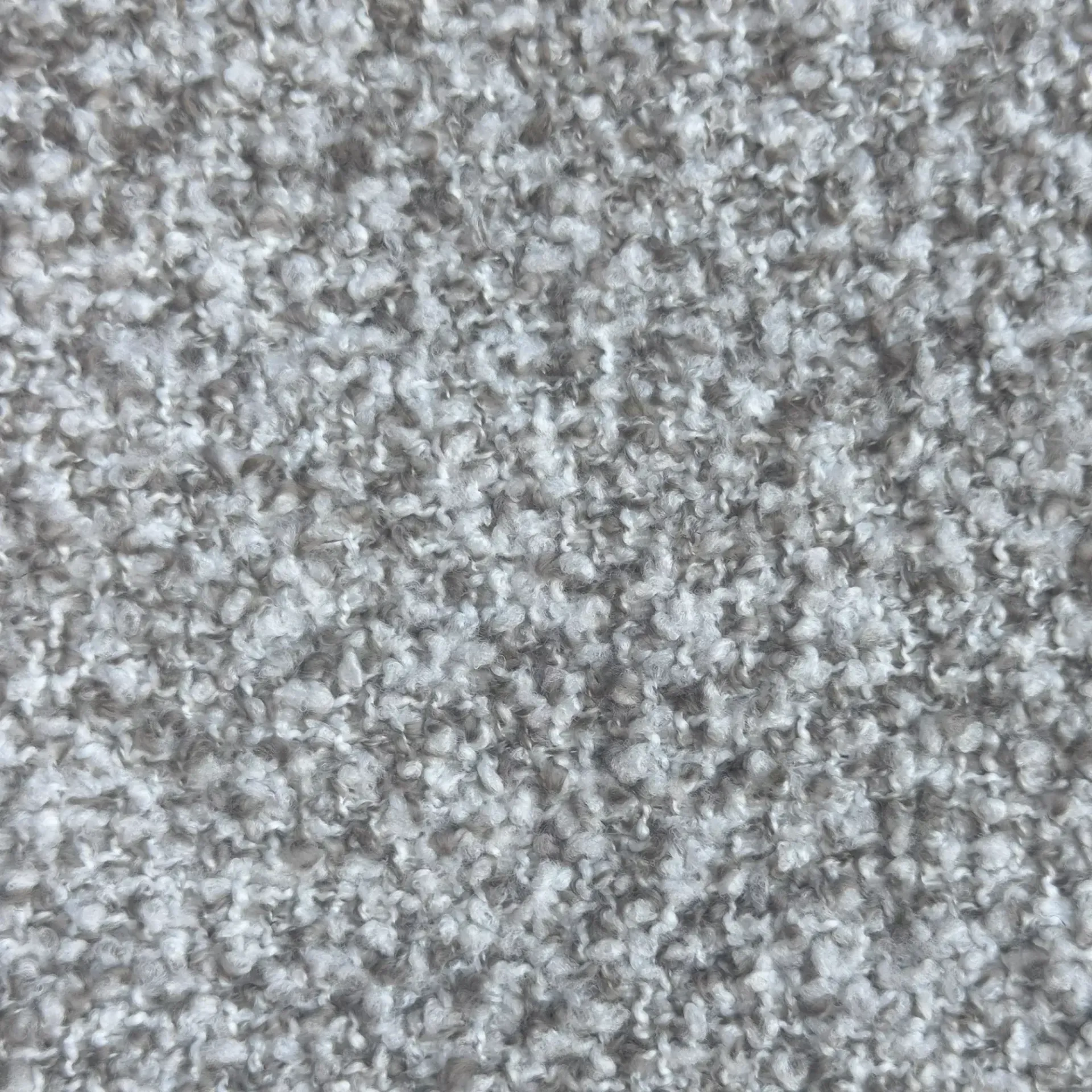 Detailopname van een grijs en wit gestructureerd tapijt.