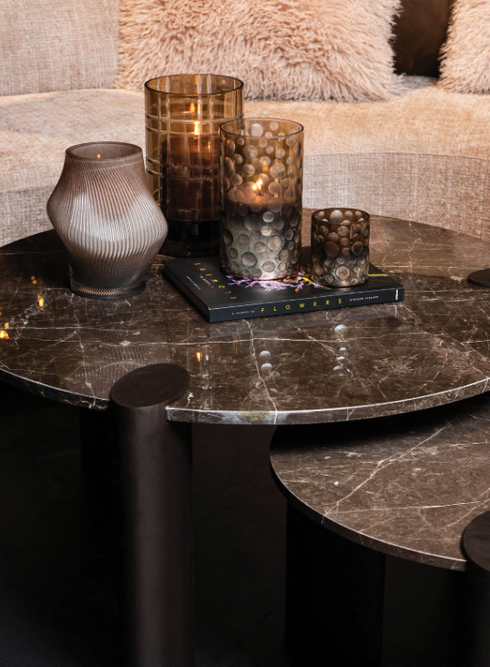 Ronde bruine tafel met drie donkere cilindrische poten op een witte achtergrond.
