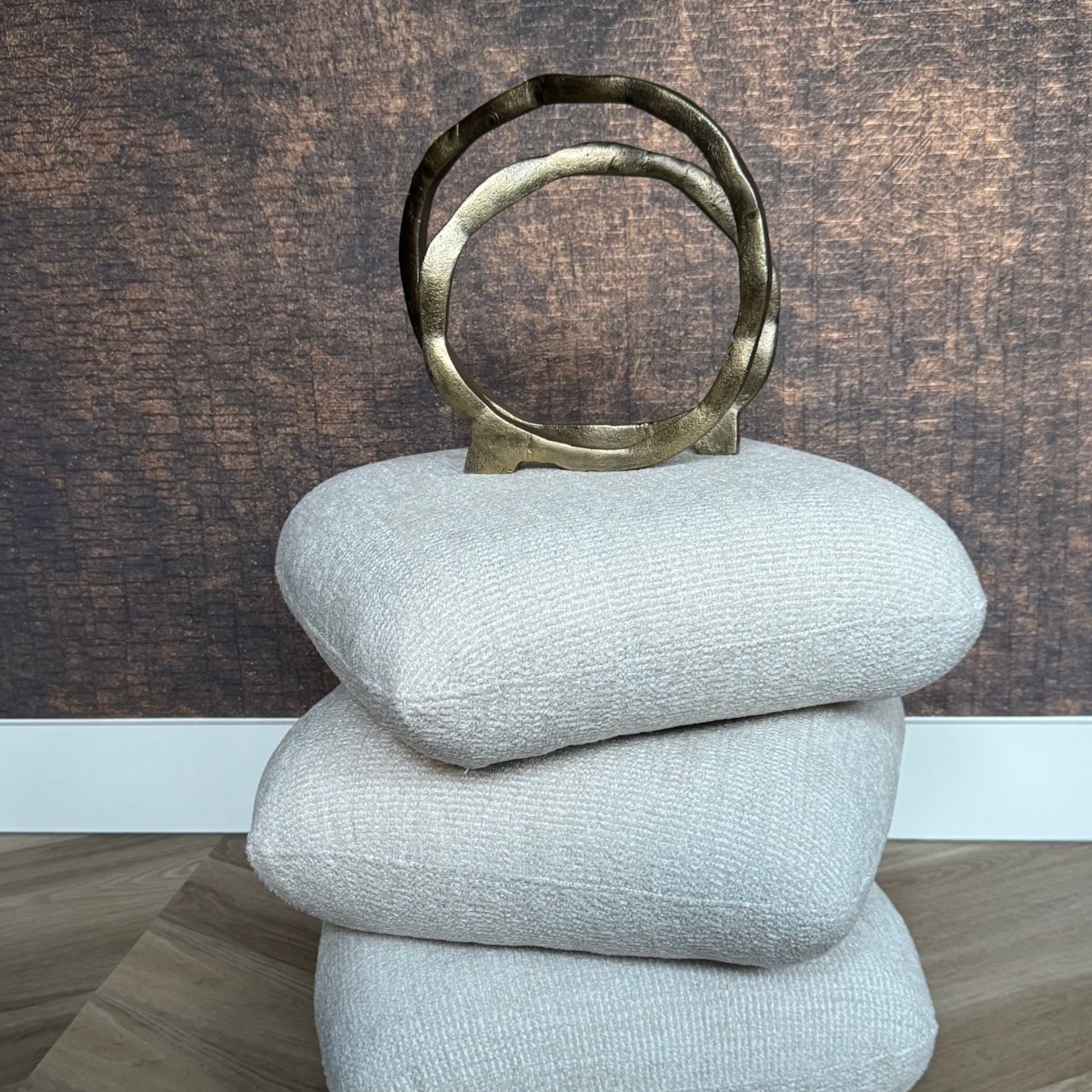 Abstracte gouden metalen sculptuur bestaande uit twee met elkaar verbonden ringen op een donker, rond oppervlak.