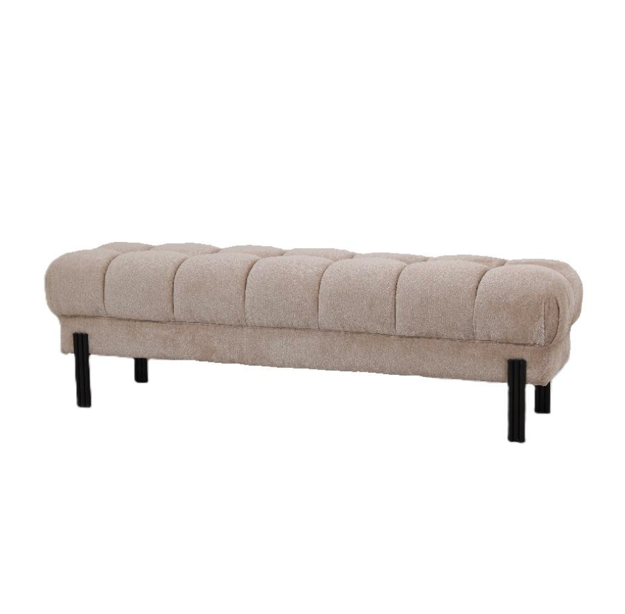 Een beige bank met gecapitonneerde bekleding en zwarte poten staat voor een donkere muur, naast een potplant en het raam.