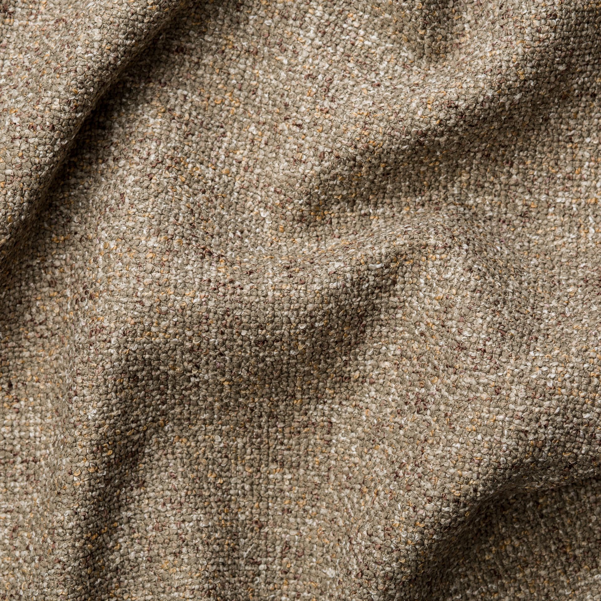 Detailopname van een beige en bruine, gestructureerde stof met zachte plooien en schaduwen.