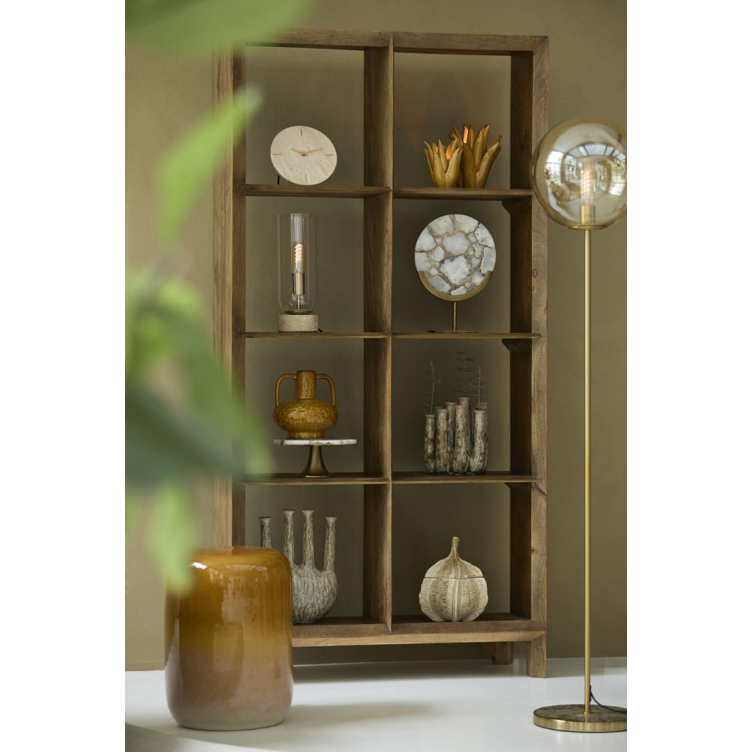 Cilindrische glazen lamp met gouden accenten op een kurken voet tegen een witte achtergrond.