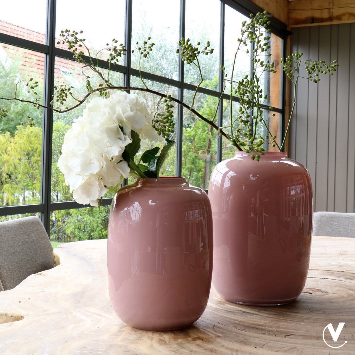 Roze, glanzende keramische vaas met een ronde vorm, die rechtop staat.