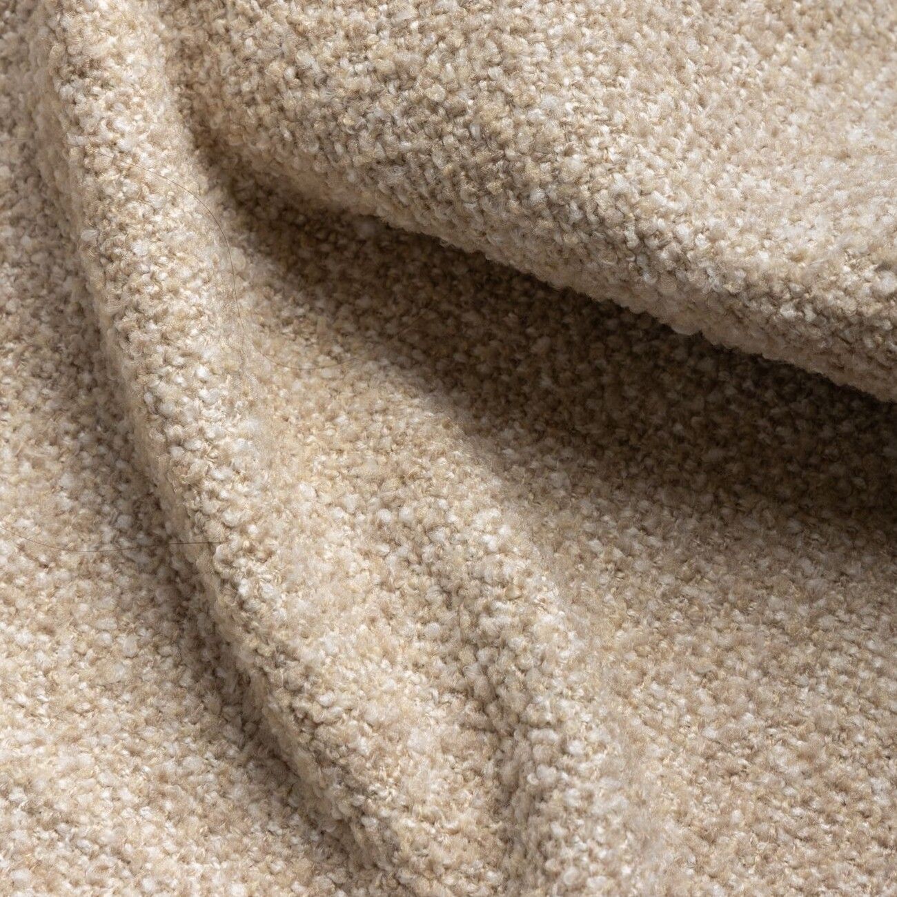 Detailopname van beige, gestructureerde stof met zachte plooien en schaduwen.