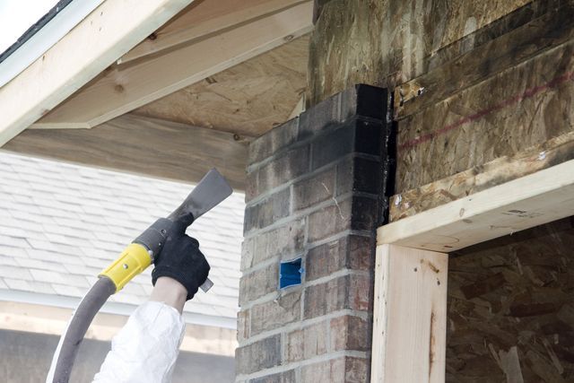 worker cleaning smoky brick on house exterior wall
