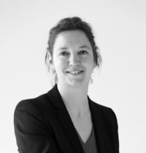 Une femme en costume sourit sur une photo en noir et blanc.