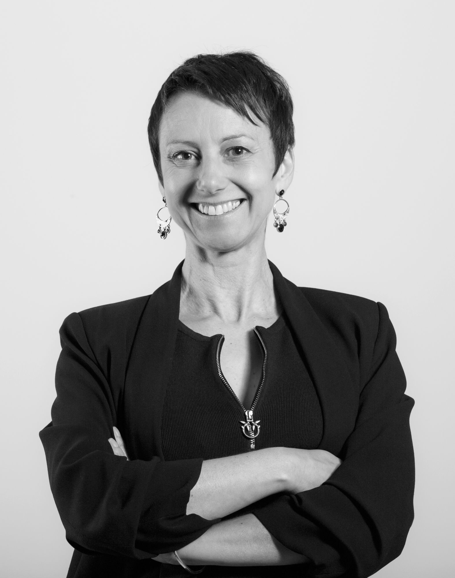 Une femme sourit avec les bras croisés sur une photo en noir et blanc.
