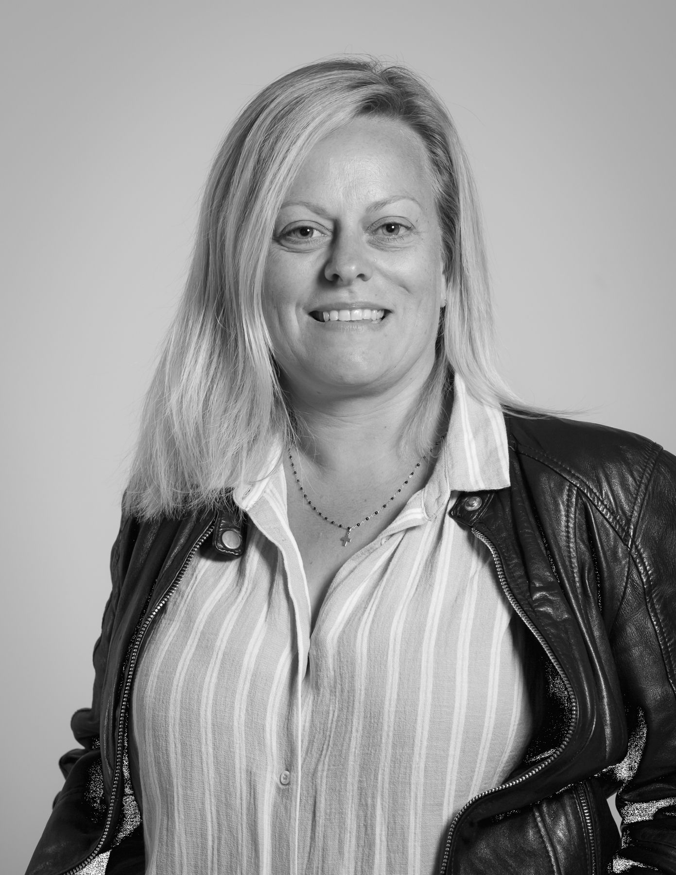 Une photo en noir et blanc d'une femme portant une veste en cuir et une chemise rayée.