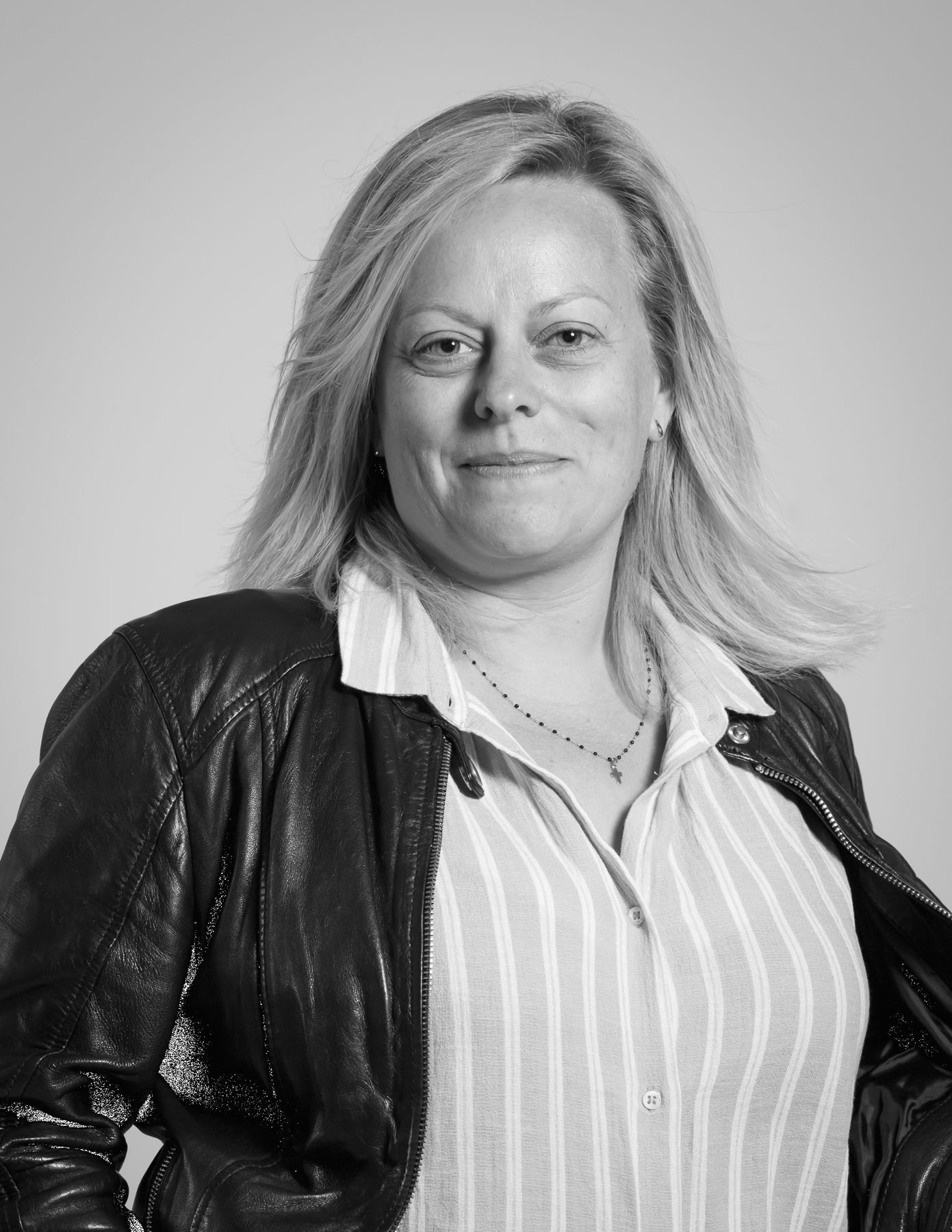 Une photo en noir et blanc d'une femme portant une veste en cuir et une chemise rayée.