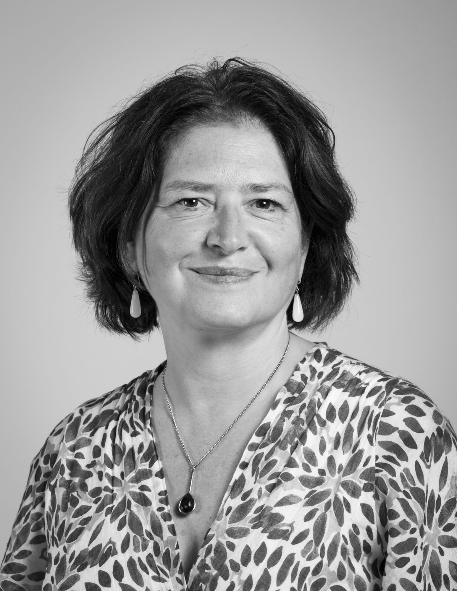Une photo en noir et blanc d'une femme portant un collier et des boucles d'oreilles.