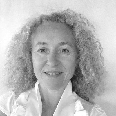 Une femme aux cheveux bouclés sourit sur une photo en noir et blanc.