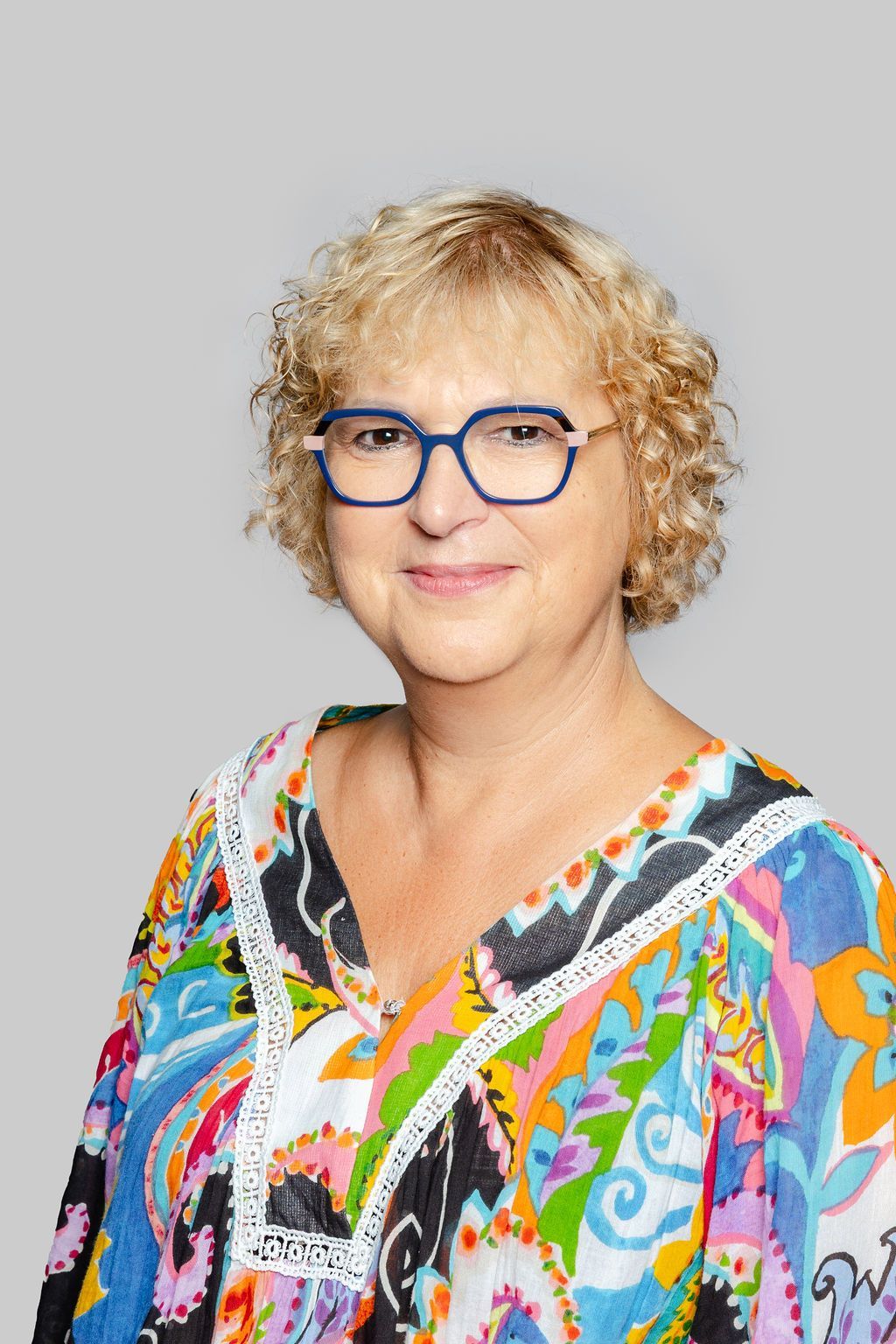 Une femme portant des lunettes et une veste noire sourit sur une photo en noir et blanc.