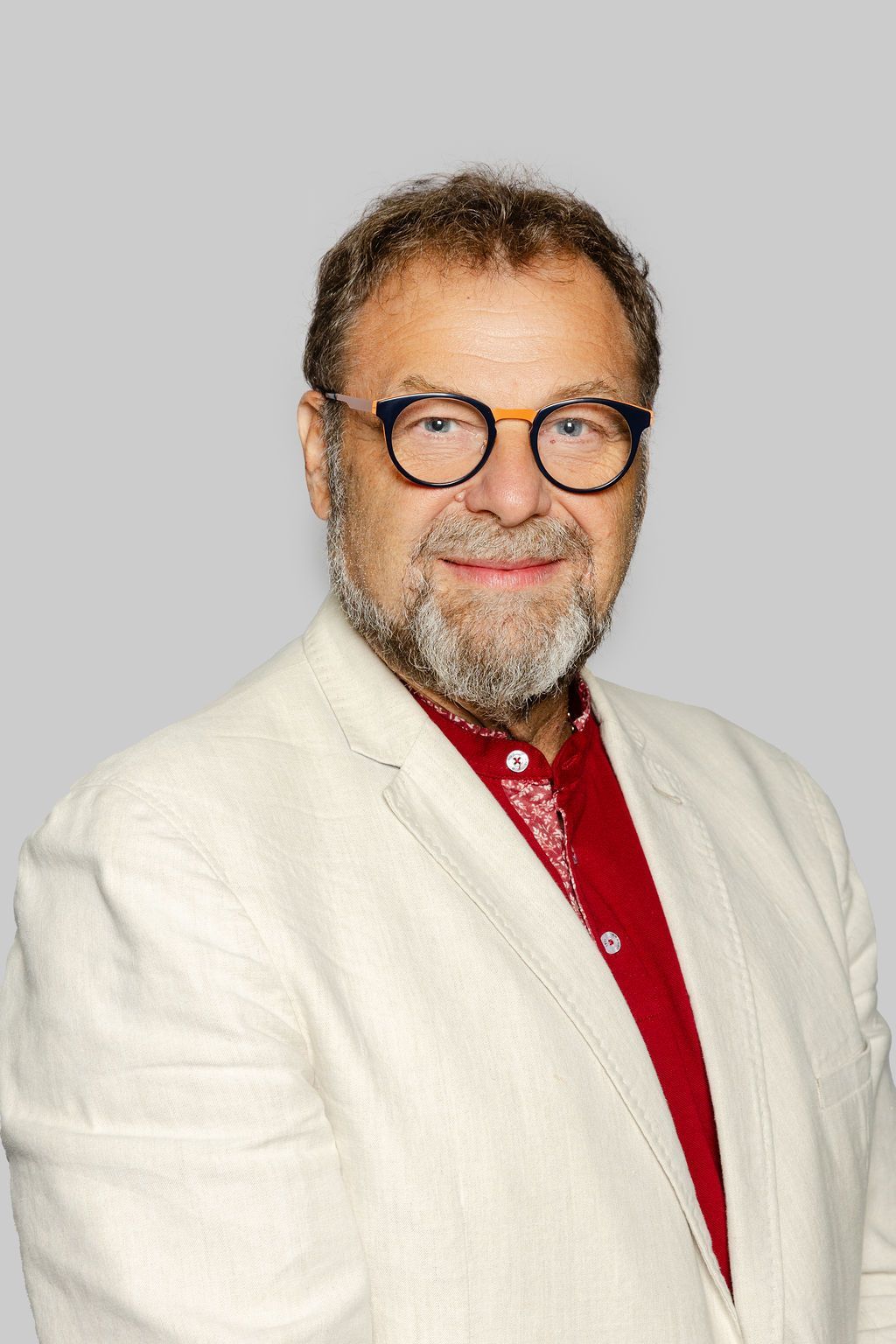 Un homme avec une barbe porte un costume et sourit sur une photo en noir et blanc.