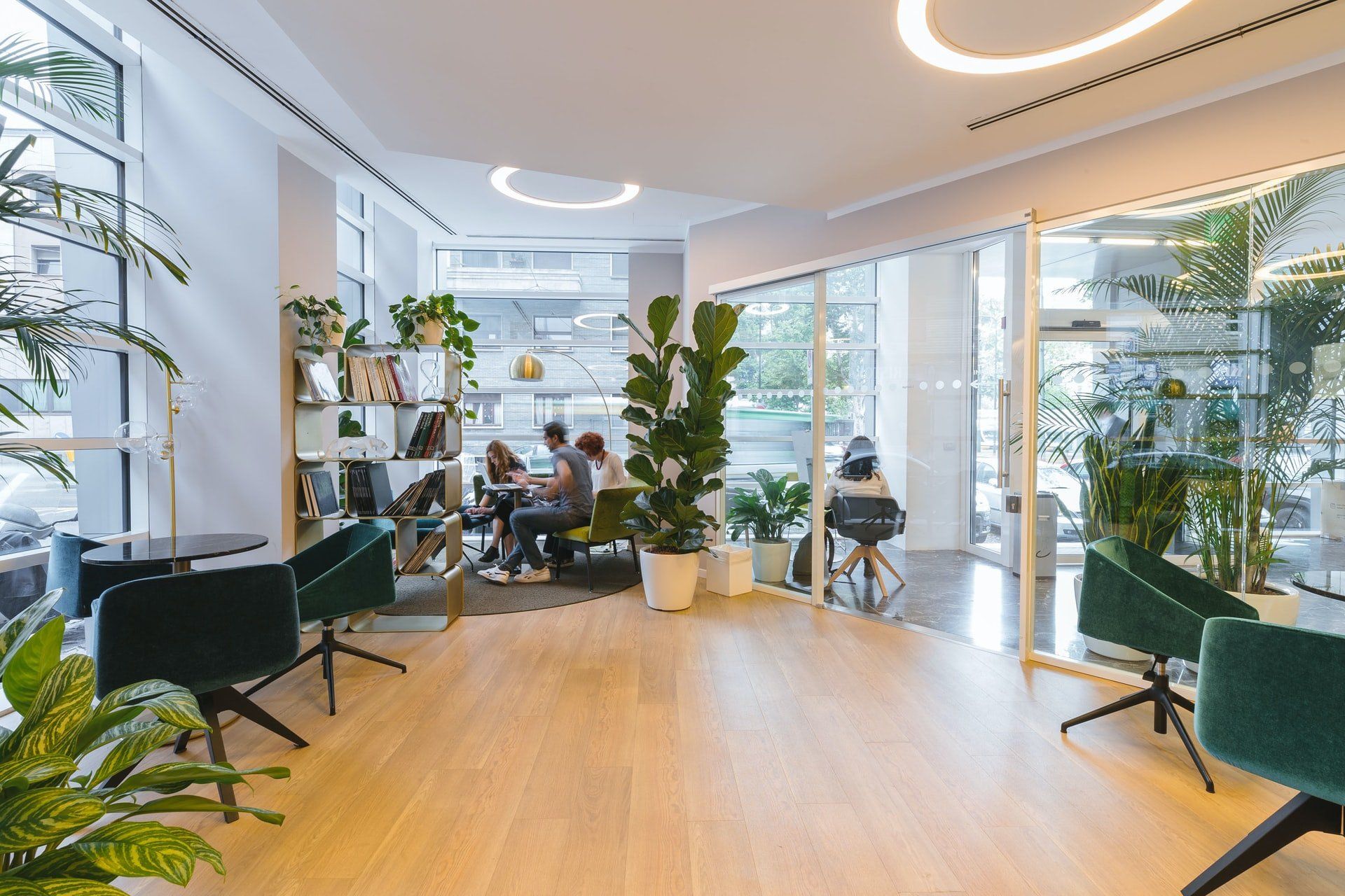 Un groupe de personnes sont assises à des tables dans une pièce avec des plantes.