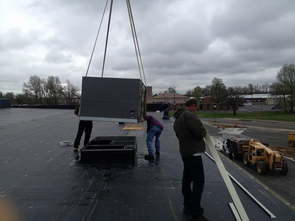 A group of men are working on a roof with a crane
