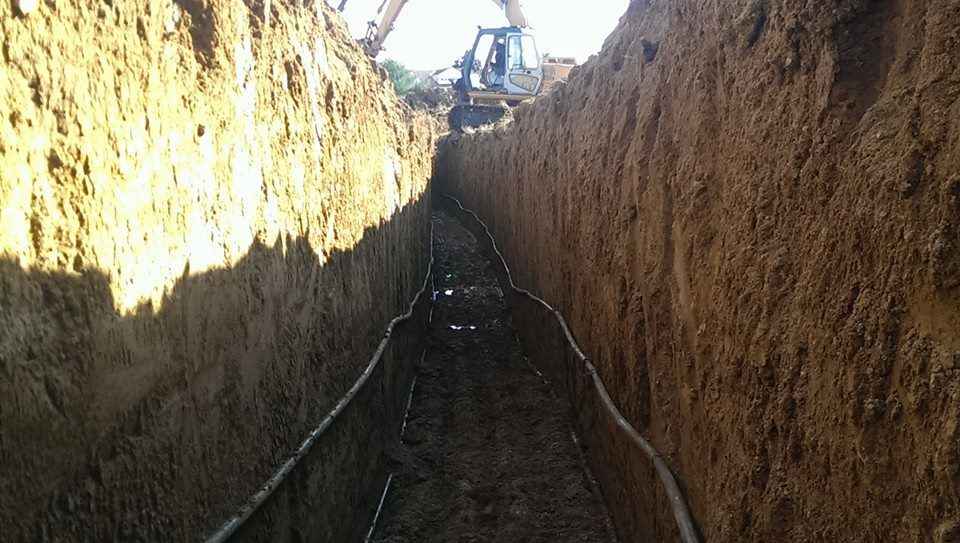 A tractor is digging a trench in the dirt.