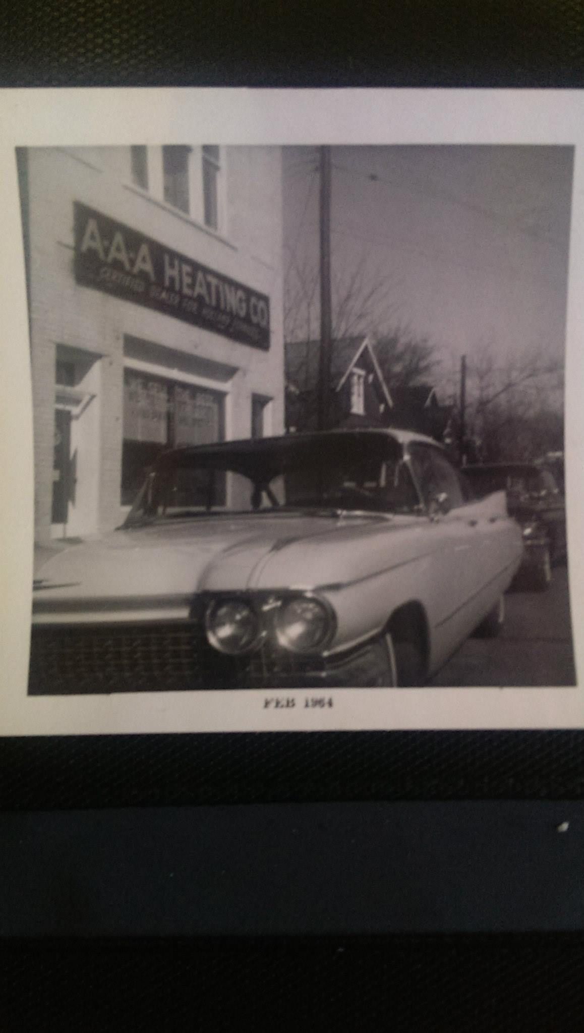 A black and white photo of a car parked in front of a building.