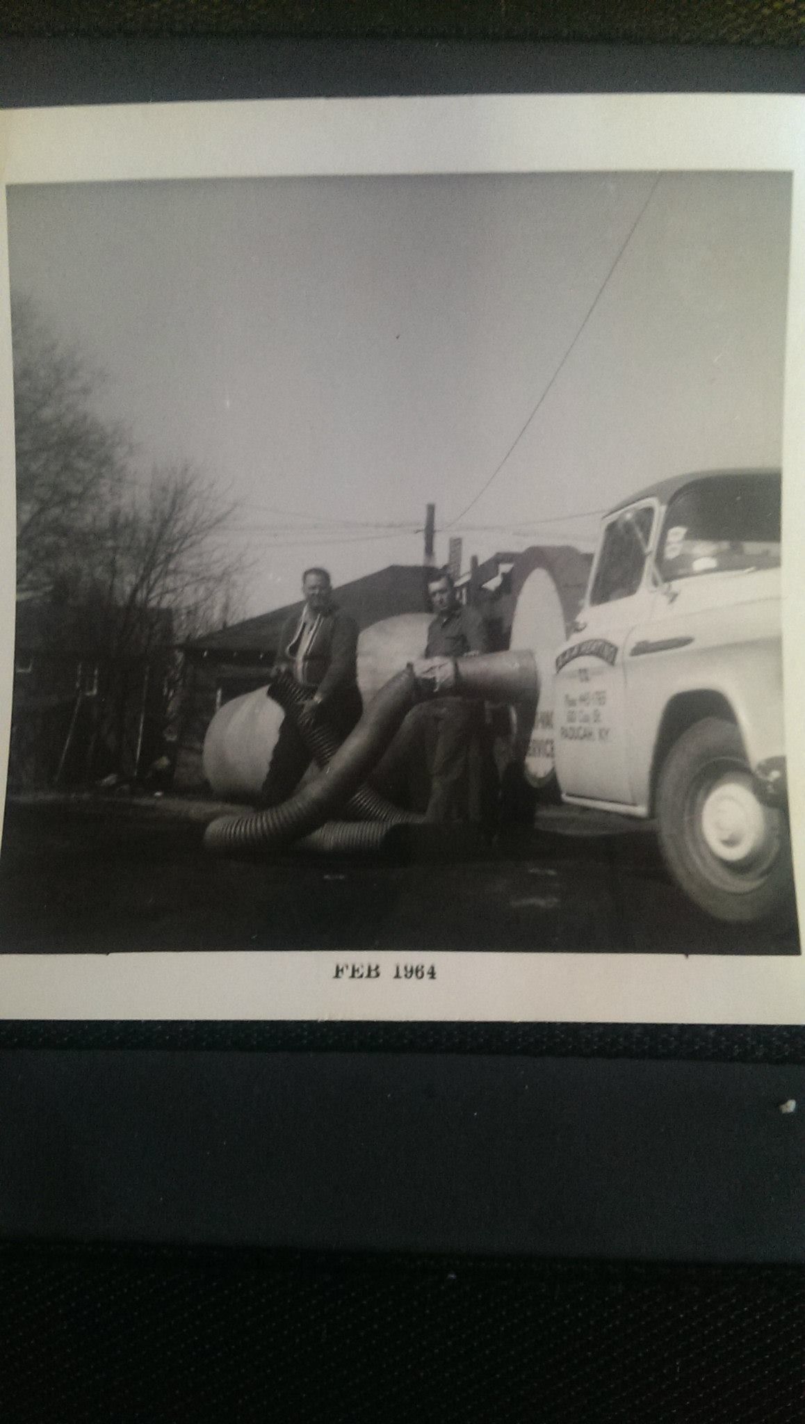 A black and white photo of a man driving a truck.