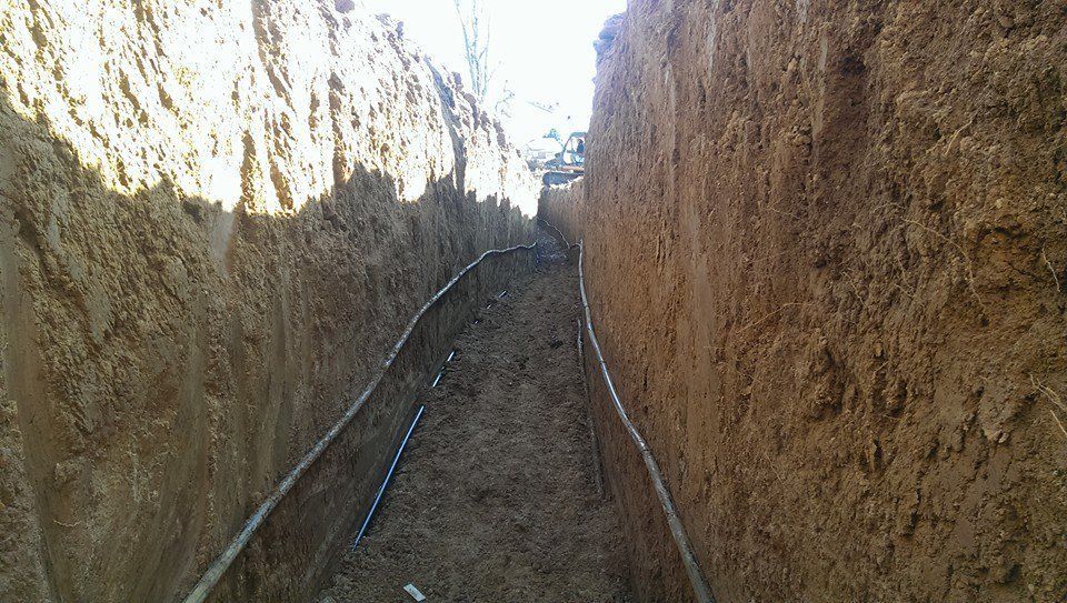 A trench filled with dirt and a hose going through it.