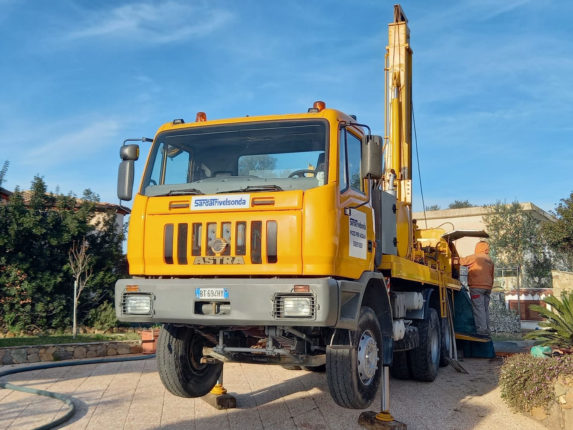 Camion di perforazione giallo su terreno asfaltato con stabilizzatori sollevati e cielo azzurro Sarda Trivelsonda Group Olbia Loiri Porto San Paolo - Loiri (SS)