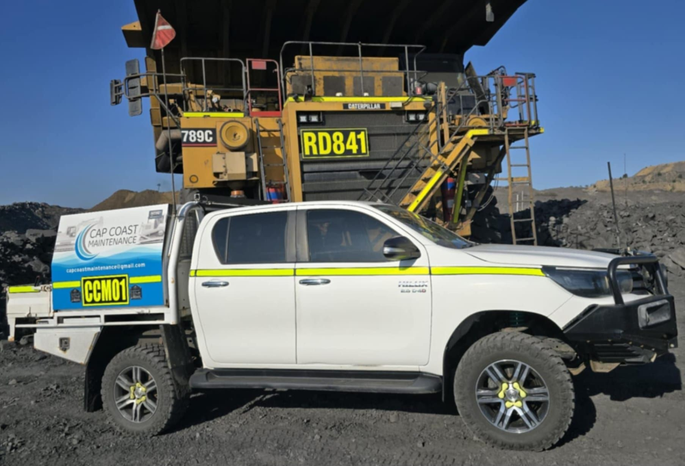 White Utility Truck Next to a Massive Yellow Mining Truck — Cap Coast Maintenance In Alton Downs, QLD