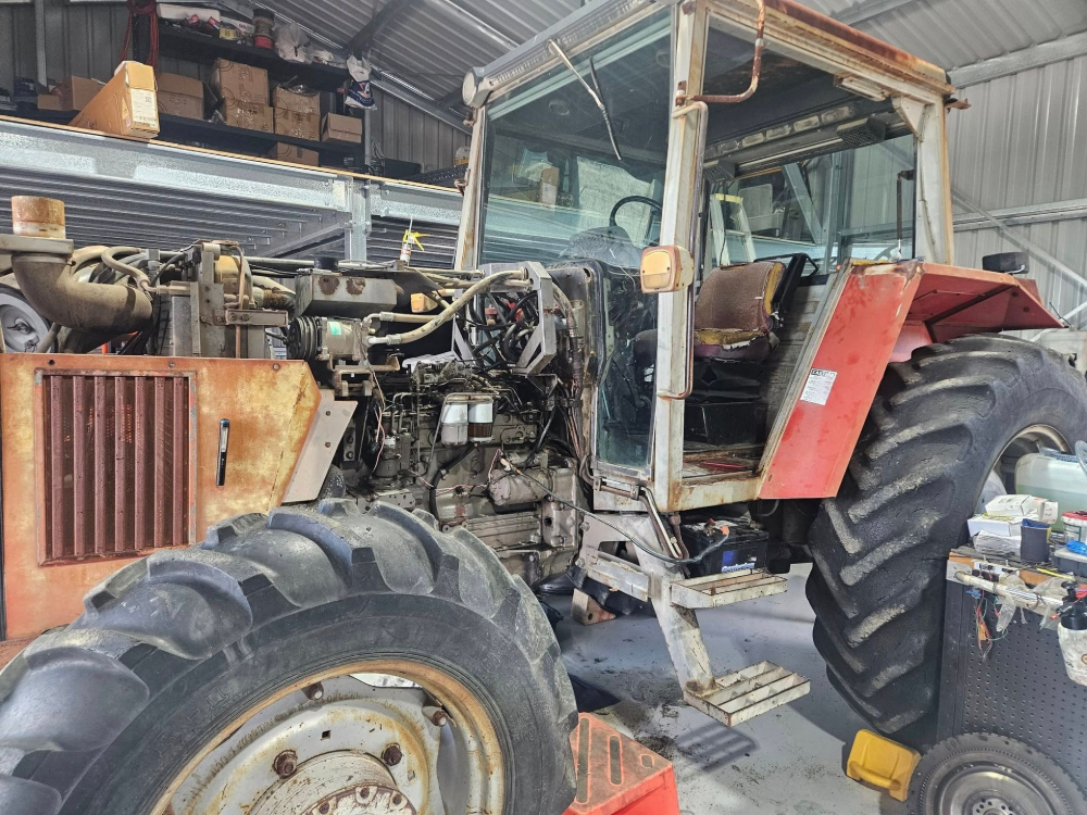 Rusty Red Tractor Being Worked on Inside a Cluttered Workshop — Cap Coast Maintenance In Alton Downs, QLD