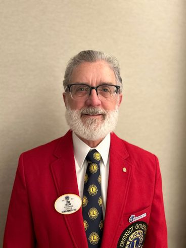 A man with a beard and glasses is wearing a red jacket and tie.