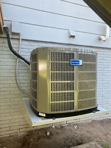 Outdoor air conditioning unit attached to a house with beige siding.