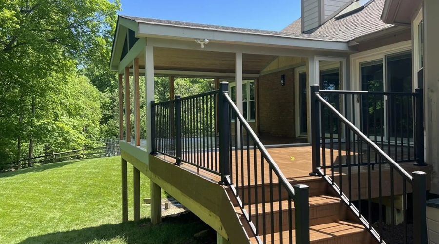 Completed outdoor backyard deck featuring brown decking, black metal railings, and a covered patio built in Fargo.