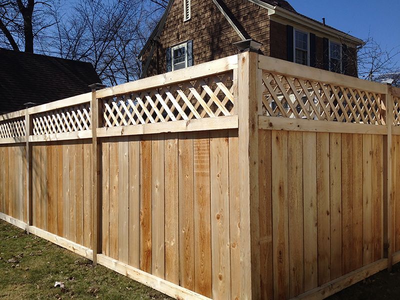 Wooden fence with lattice top in front of a house.