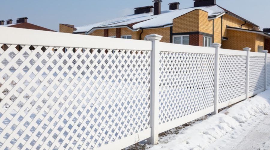 White lattice vinyl fence installed in a snowy Fargo yard
