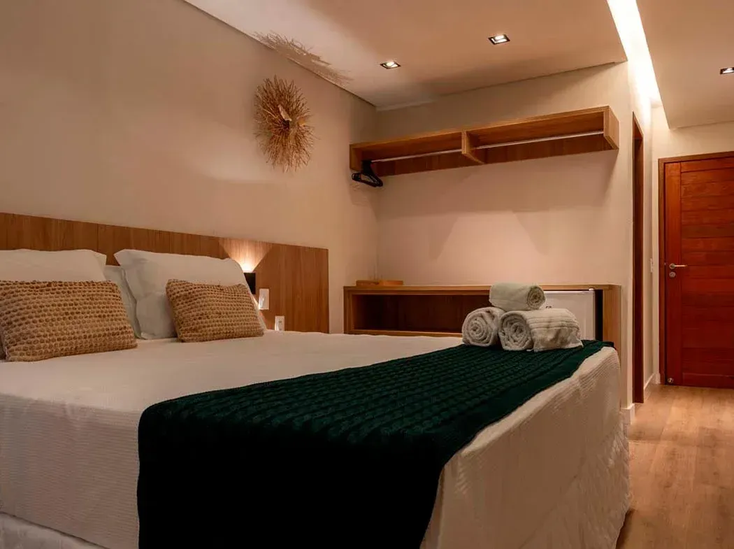 Um quarto de hotel com cama, toalhas e um relógio na parede.