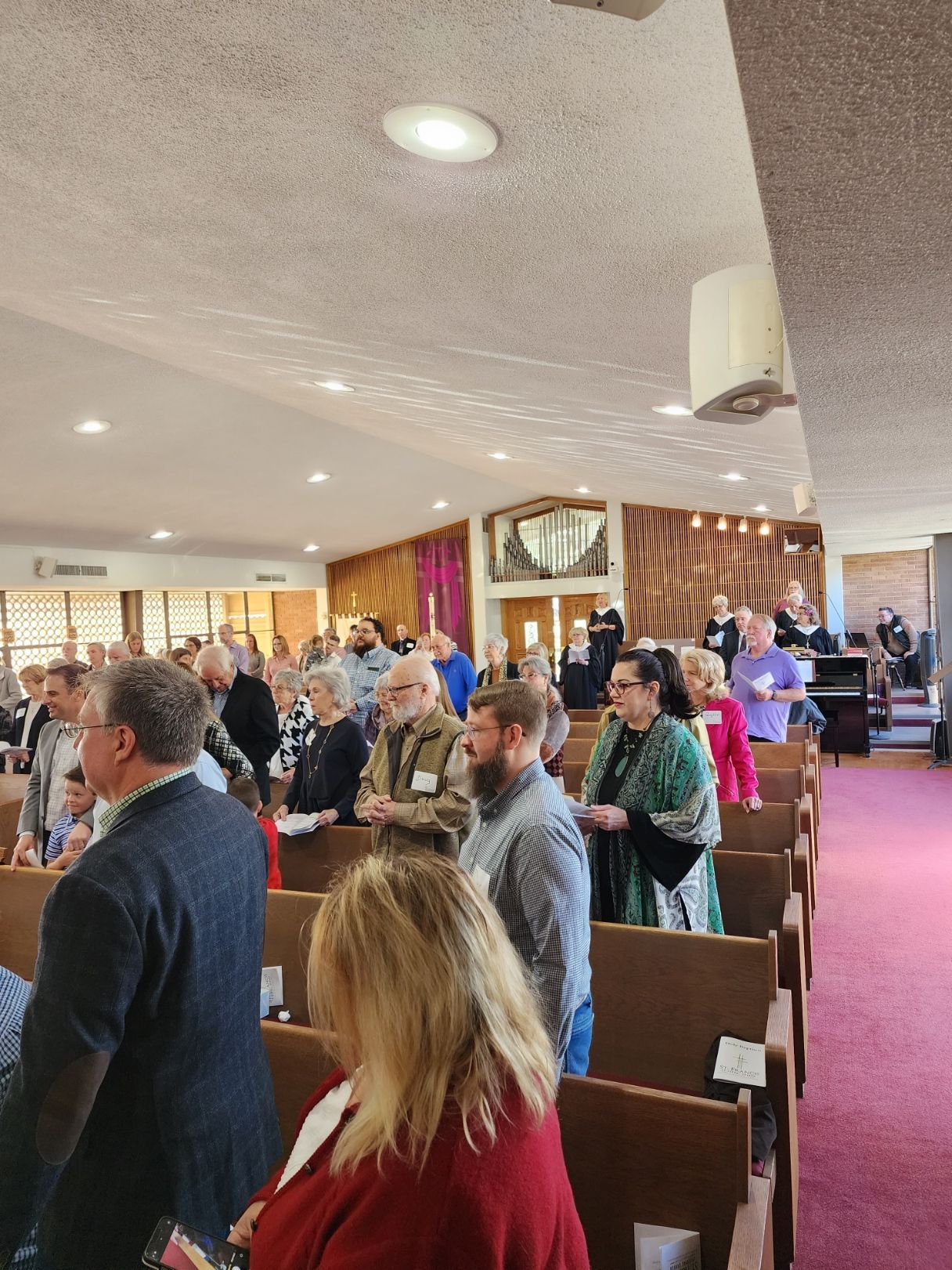 People standing and facing forward in a church, likely during a service.