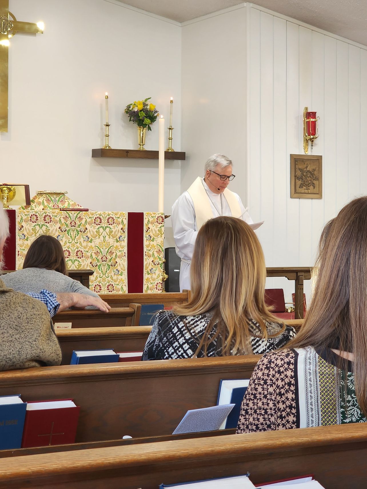 Pastor reading from the pulpit in a church. Congregation seated in pews.