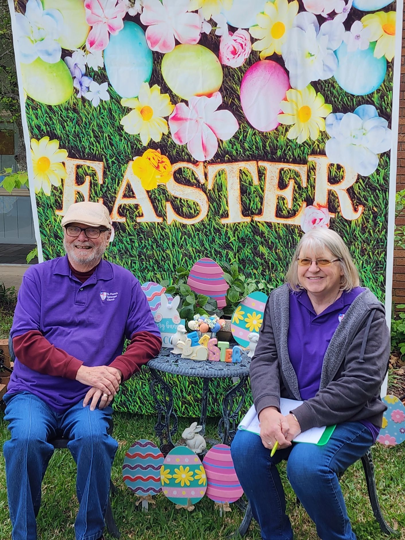 Two people in purple, sitting in front of Easter decorations.