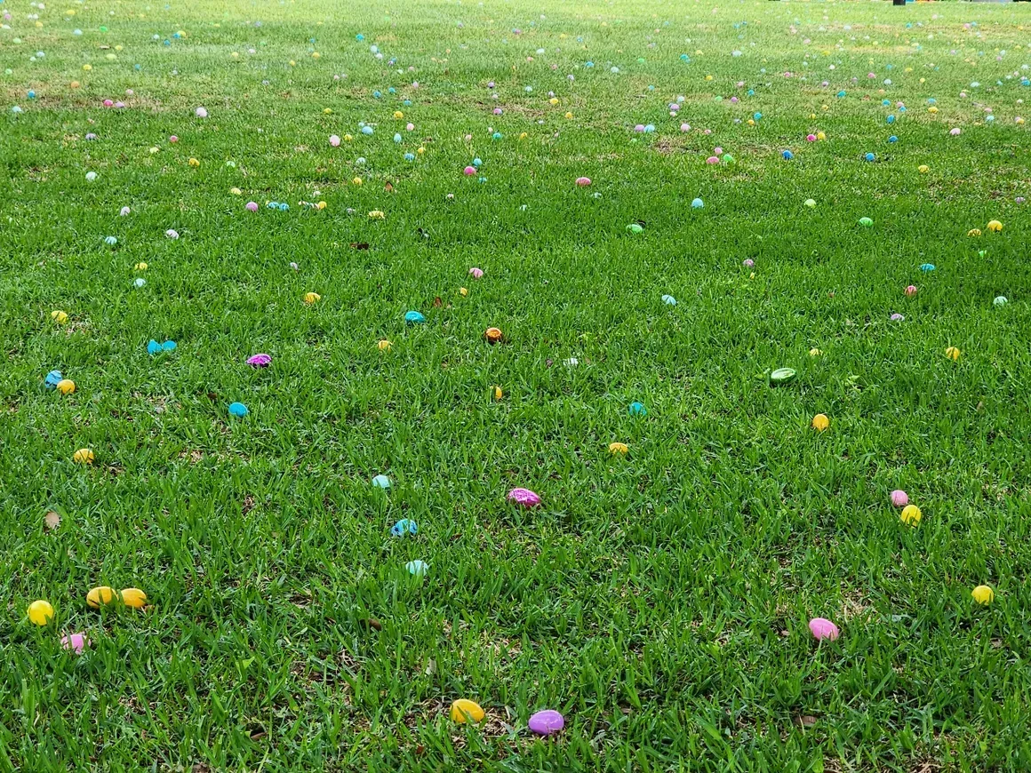 Green grass with scattered, colorful Easter eggs.