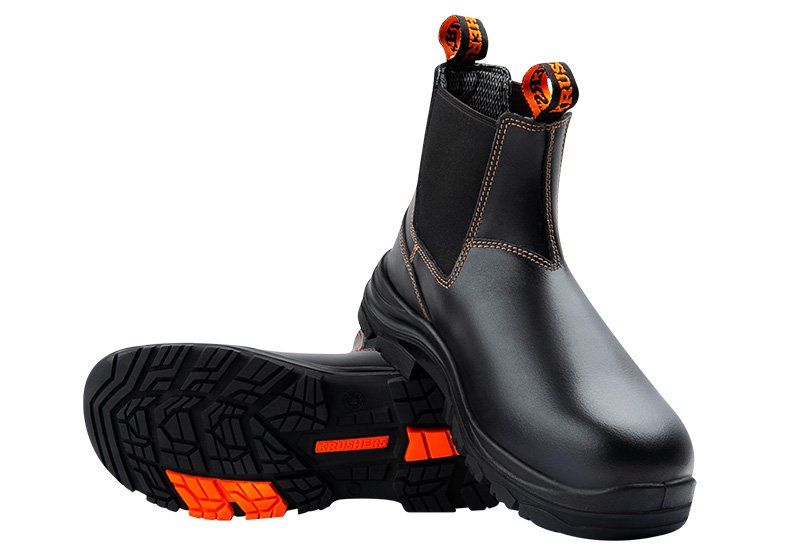 A pair of black and orange safety boots on a white background.