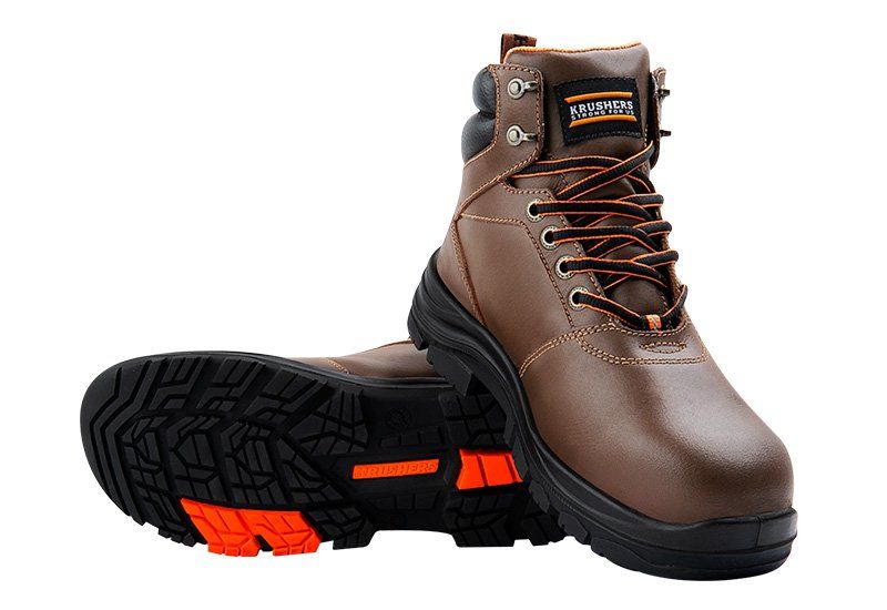 A pair of brown safety boots with orange soles on a white background.