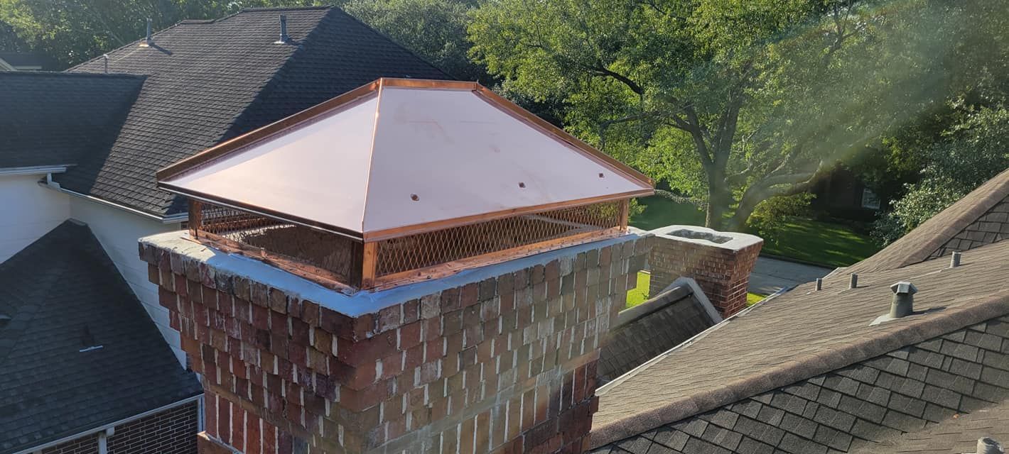 Copper chimney cap on a brick chimney, surrounded by rooftops and trees.