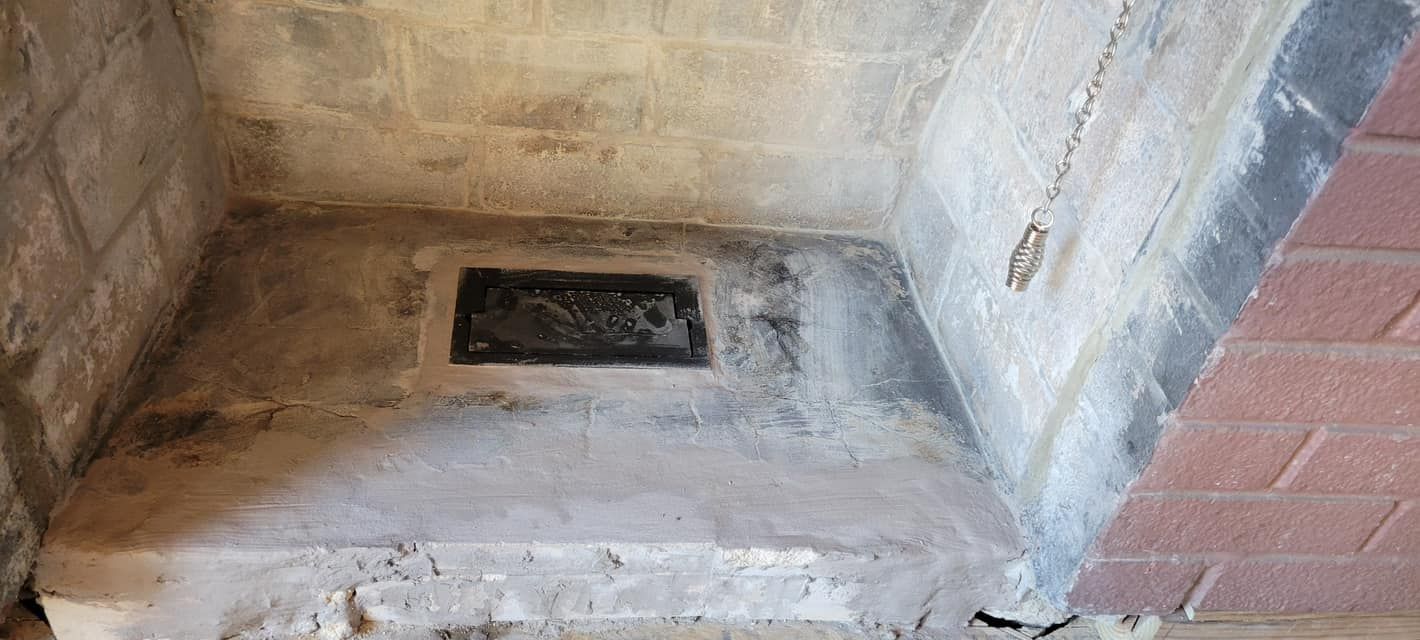 Interior of a brick fireplace, showing a vent on the upper back wall.
