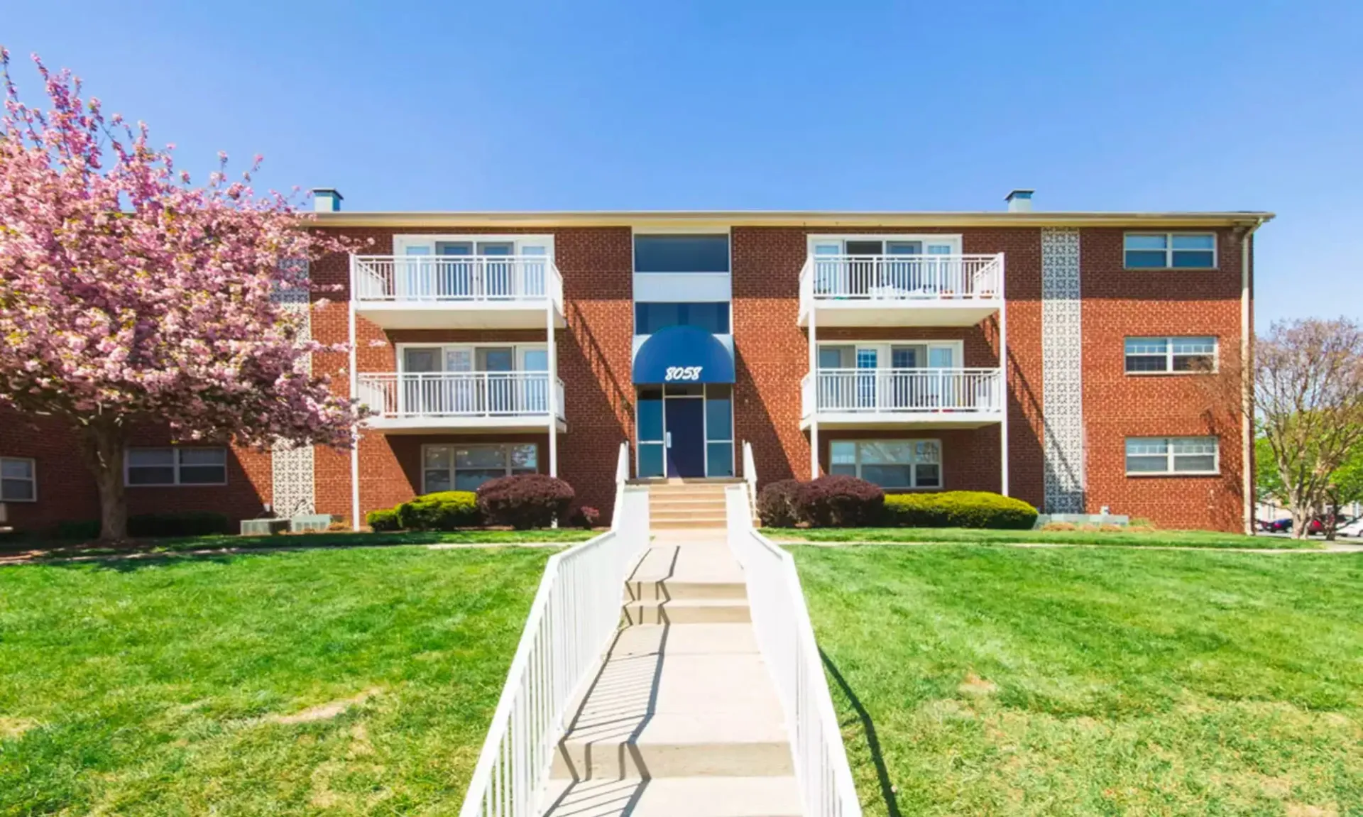 A large brick apartment building with a ramp leading to the front door at Westgate Apartments & Townhomes in Manassas, VA.