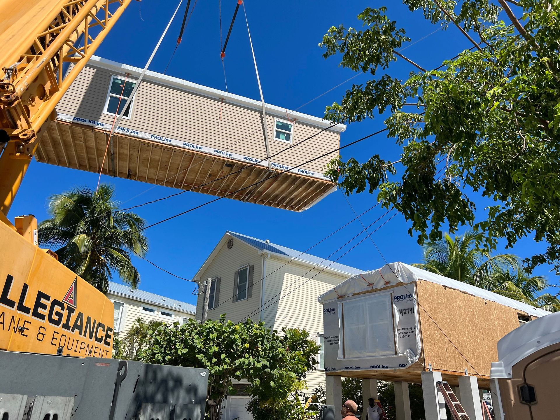 Modern white beach house with balconies and palm trees under a blue sky