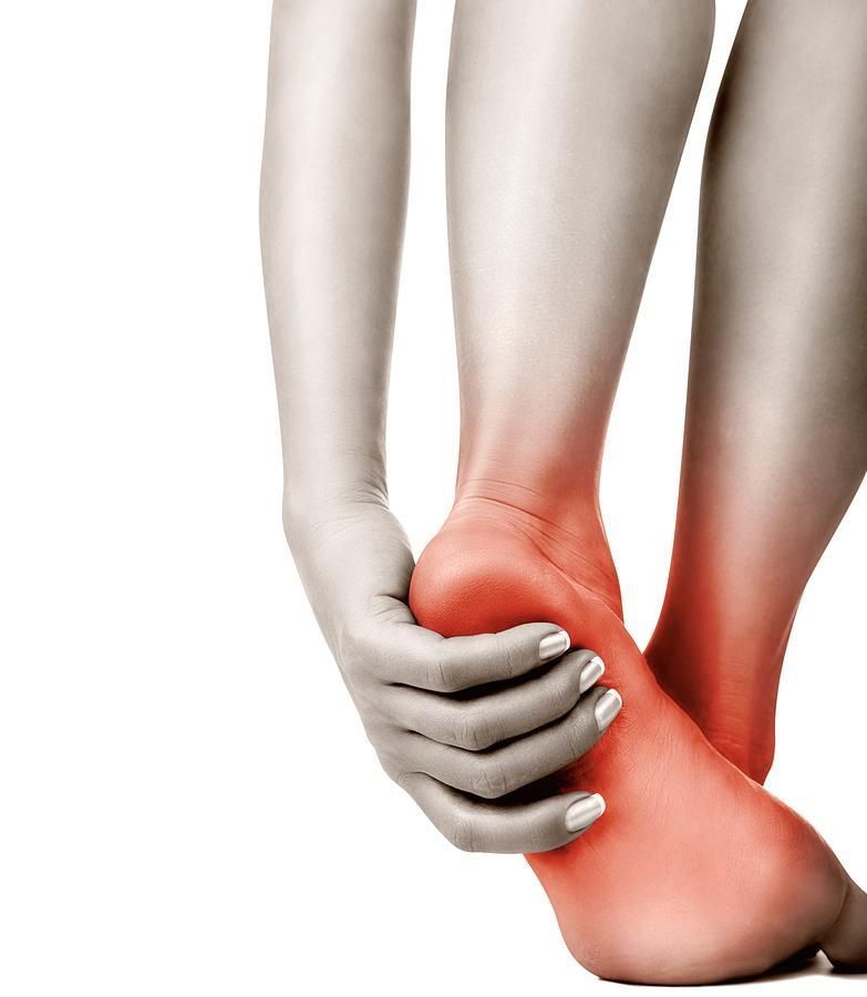 Woman holding her red, painful heel.