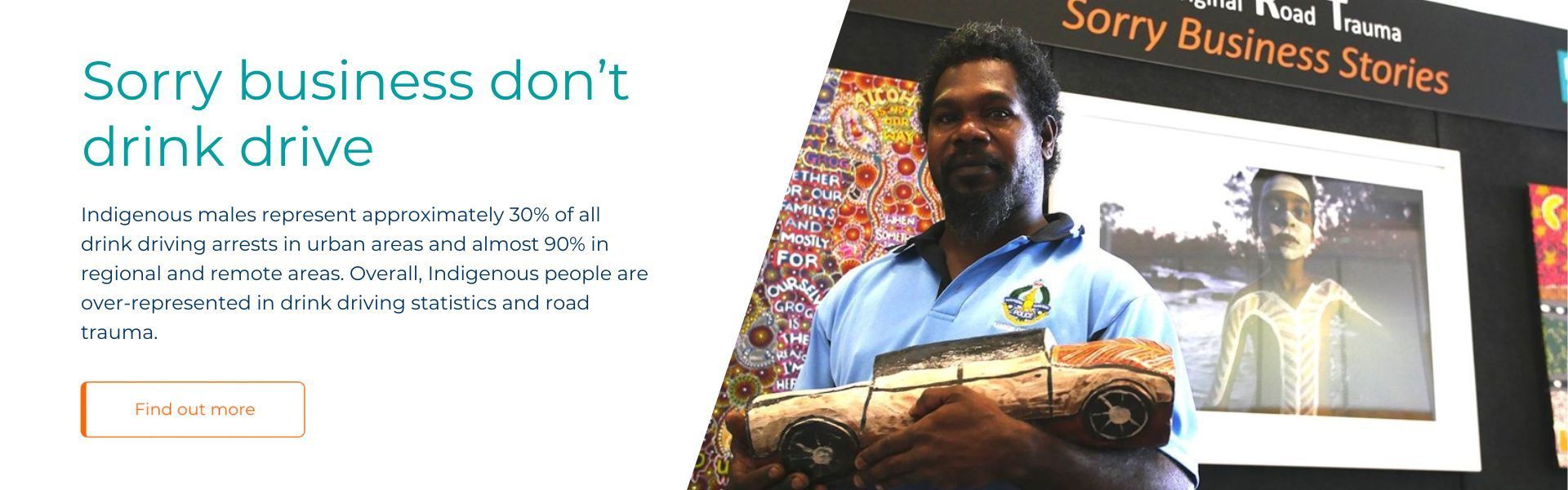 A man is holding a car in front of a sign that says sorry business do n't drink drive