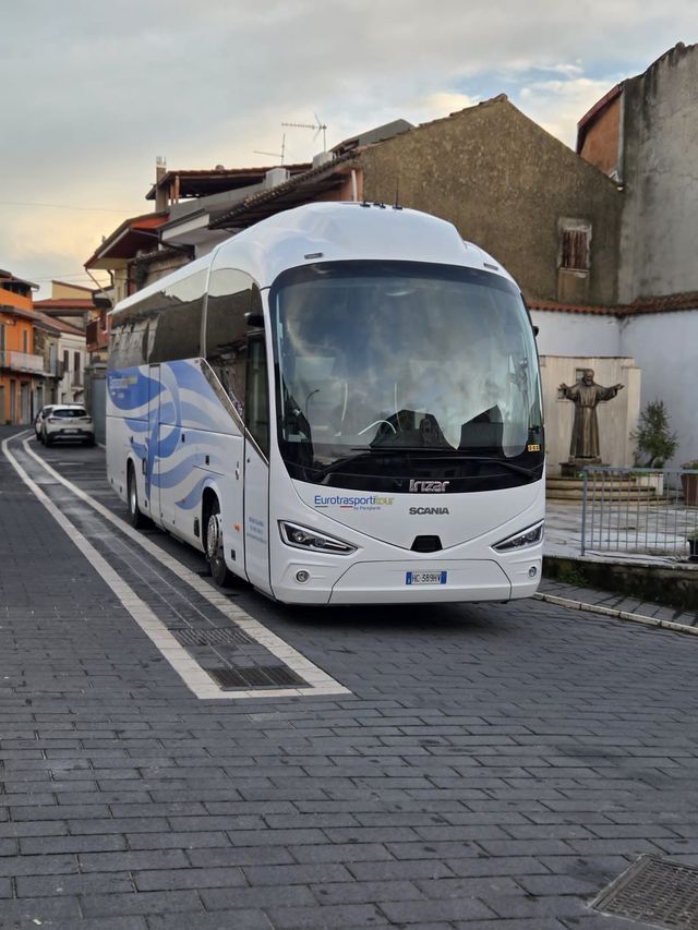 Autobus bianco parcheggiato su una strada acciottolata in un tranquillo quartiere residenziale.
