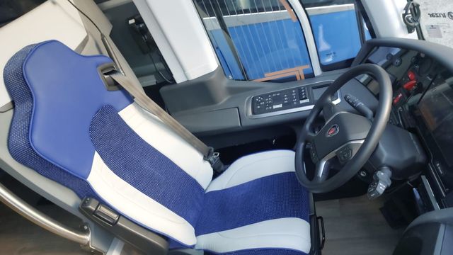 Sedile da corsa e volante blu e bianchi all'interno dell'abitacolo di un veicolo.